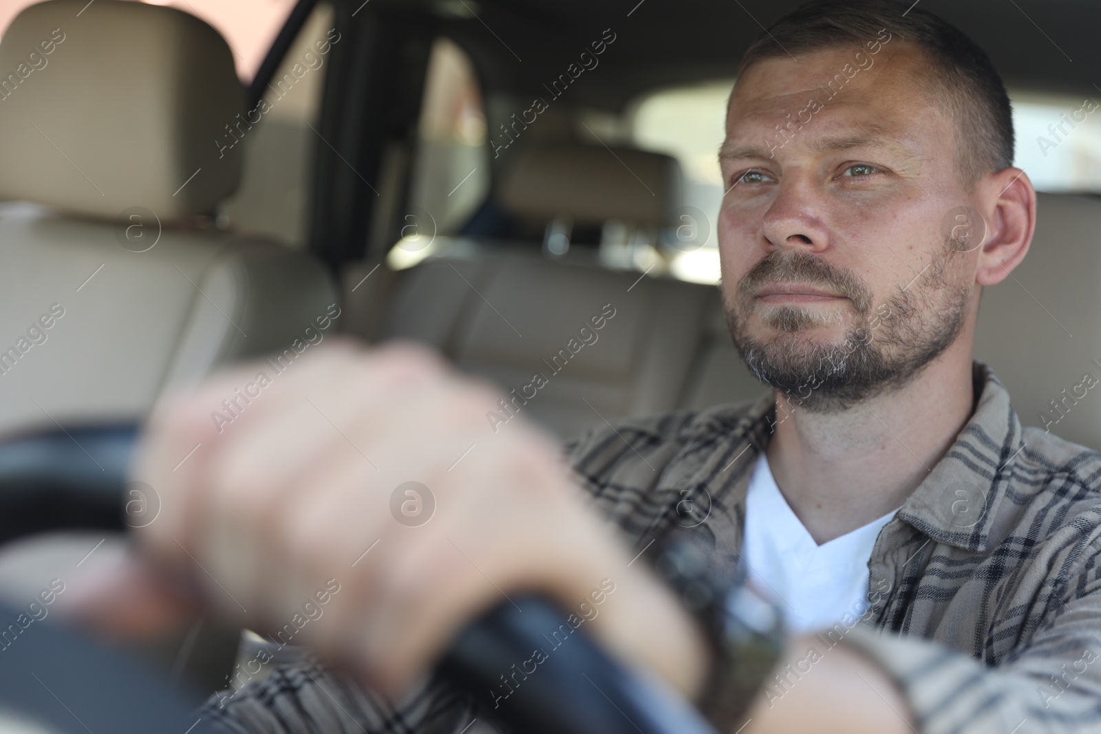 Photo of Man holding steering wheel while driving car, view through windshield