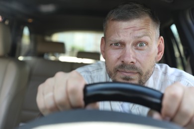 Photo of Man holding steering wheel while driving car, view through windshield