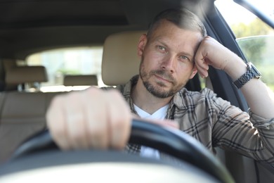 Photo of Man holding steering wheel while driving car, view through windshield