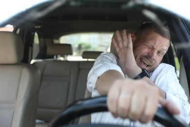 Photo of Emotional man holding steering wheel while driving car, view through windshield