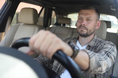 Photo of Man holding steering wheel while driving car, view through windshield