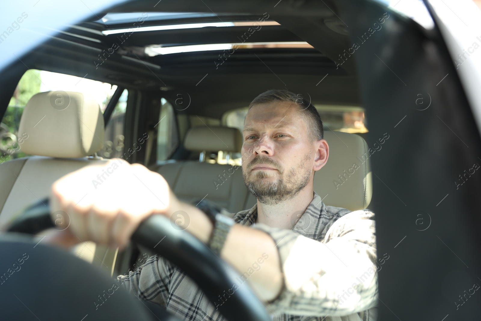 Photo of Man holding steering wheel while driving car, view through windshield