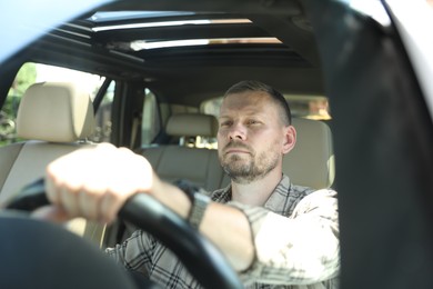 Man holding steering wheel while driving car, view through windshield