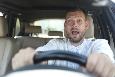 Photo of Emotional man holding steering wheel while driving car, view through windshield