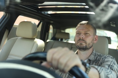 Photo of Man holding steering wheel while driving car, view through windshield