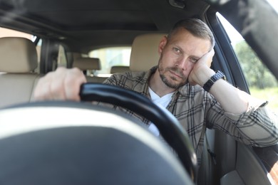 Photo of Man holding steering wheel while driving car, view through windshield