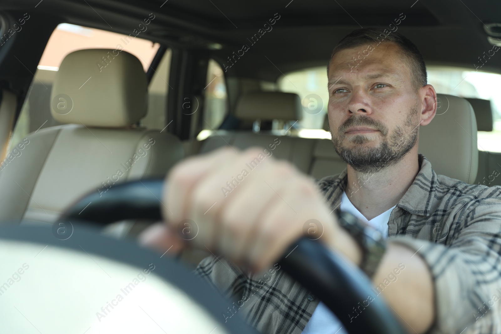 Photo of Man holding steering wheel while driving car, view through windshield