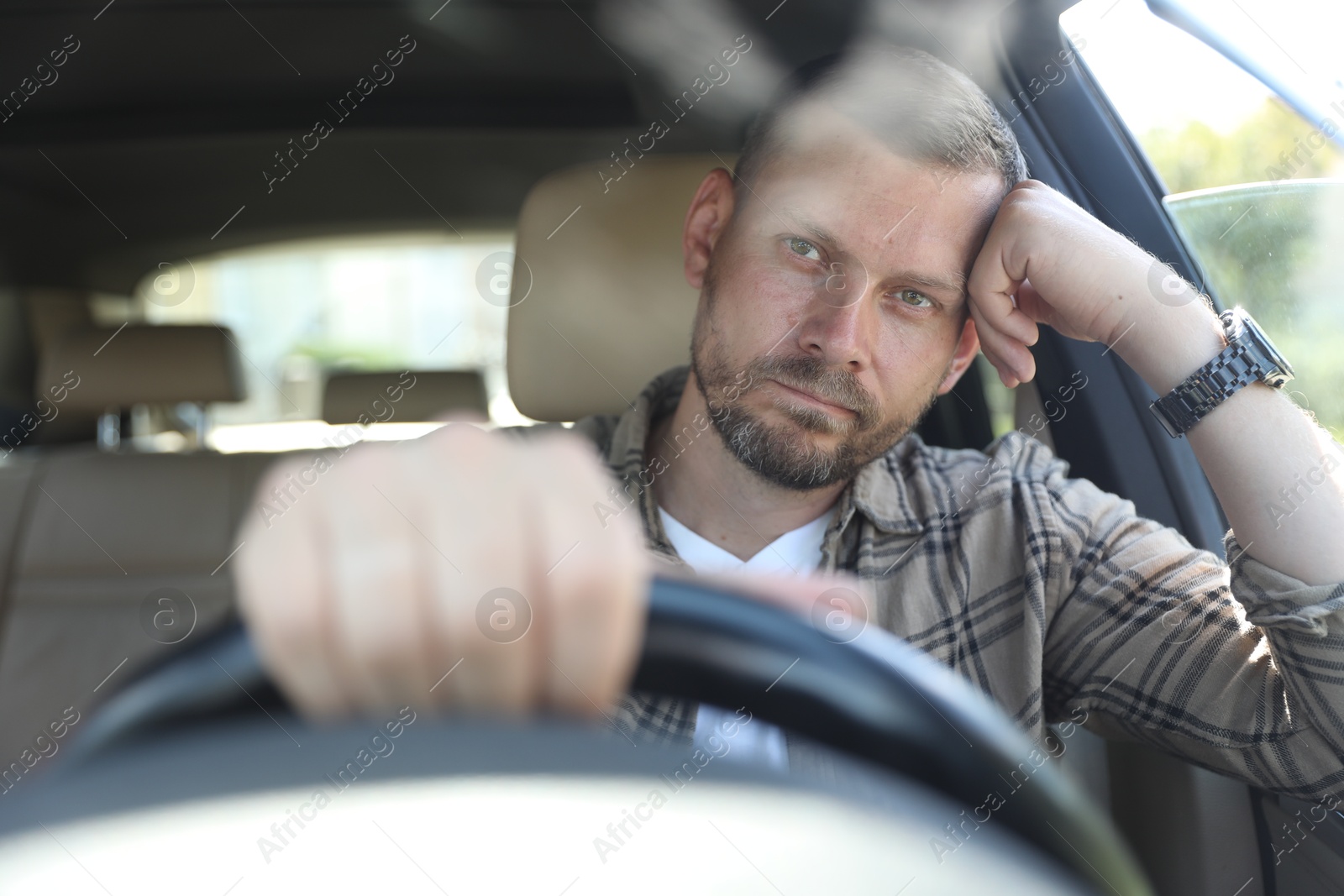 Photo of Man holding steering wheel while driving car, view through windshield