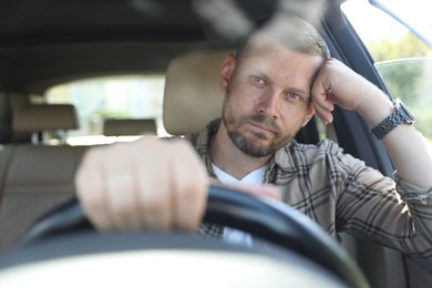 Man holding steering wheel while driving car, view through windshield