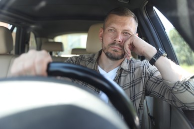 Photo of Man holding steering wheel while driving car, view through windshield