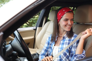 Smiling woman fastening safety seat in car, view from outside