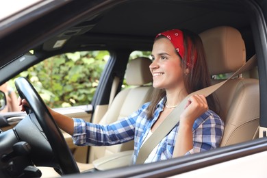 Photo of Smiling woman holding steering wheel while driving car, view from outside