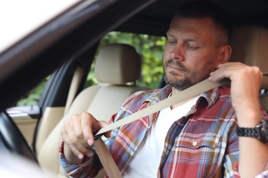 Man fastening safety seat inside modern car