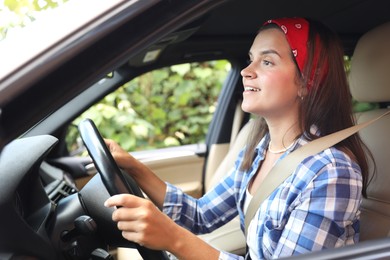 Photo of Woman holding steering wheel while driving car, view from outside