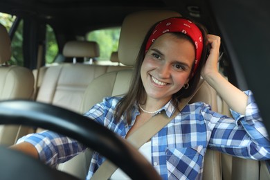 Photo of Smiling woman holding steering wheel while driving car