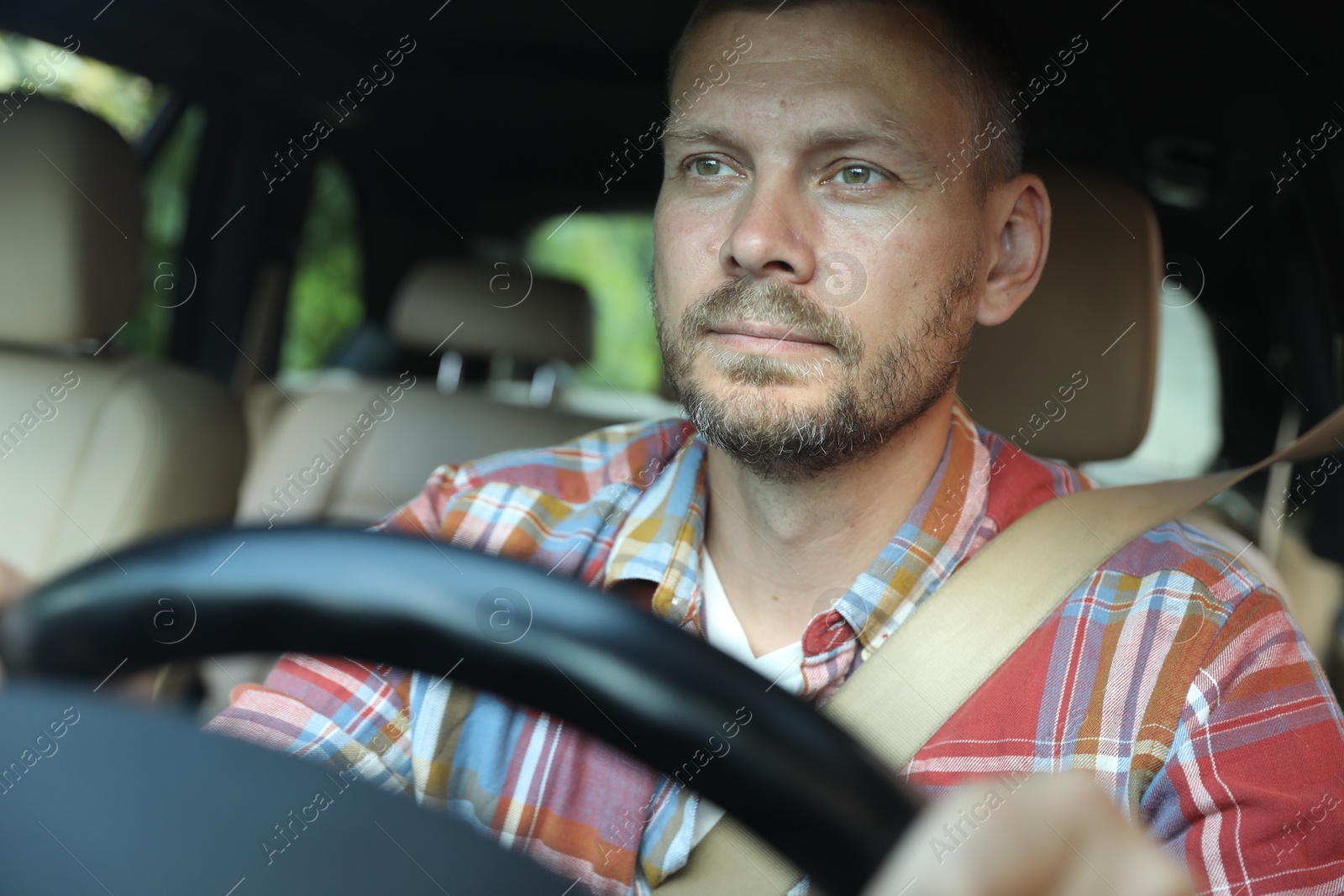 Photo of Man holding steering wheel while driving car, view through windshield