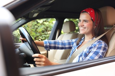 Smiling woman holding steering wheel while driving car, view from outside