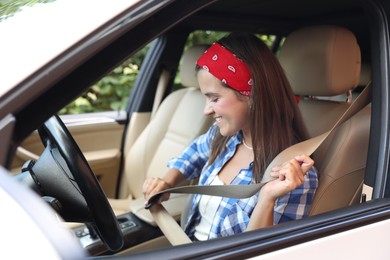 Smiling woman fastening safety seat inside car