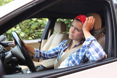 Emotional woman holding steering wheel while driving car, view from outside