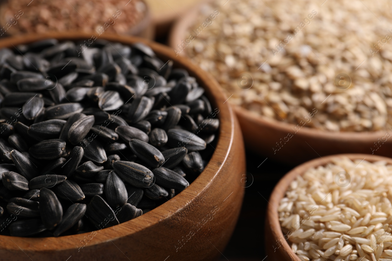 Photo of Different cereals and seeds in bowls on table, closeup