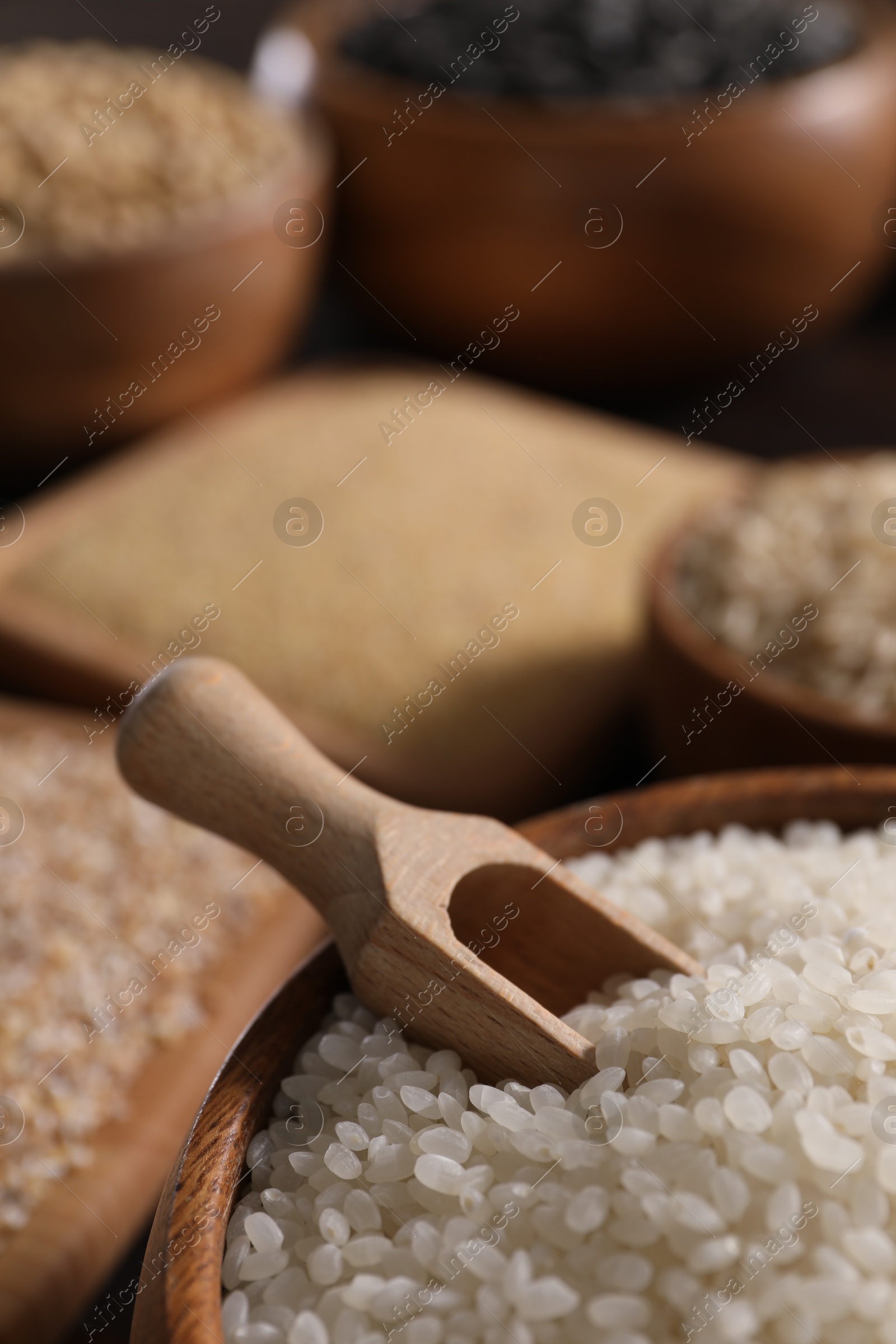 Photo of Rice and scoop in wooden bowl on table, closeup