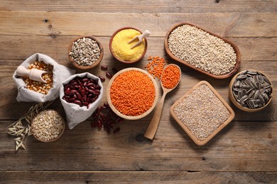 Photo of Different types of cereals, seeds and legumes on wooden table, flat lay