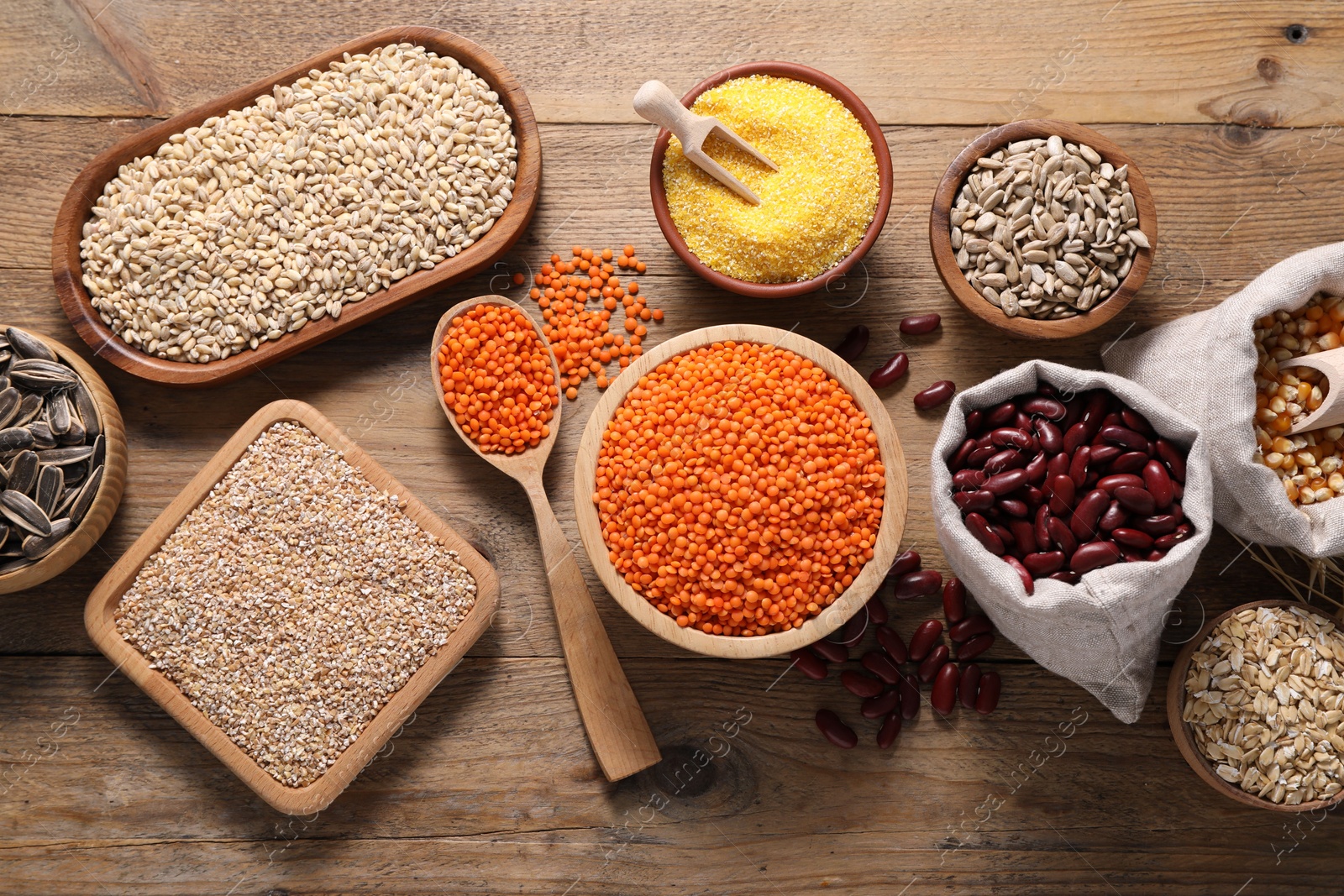 Photo of Different types of cereals, seeds and legumes on wooden table, flat lay