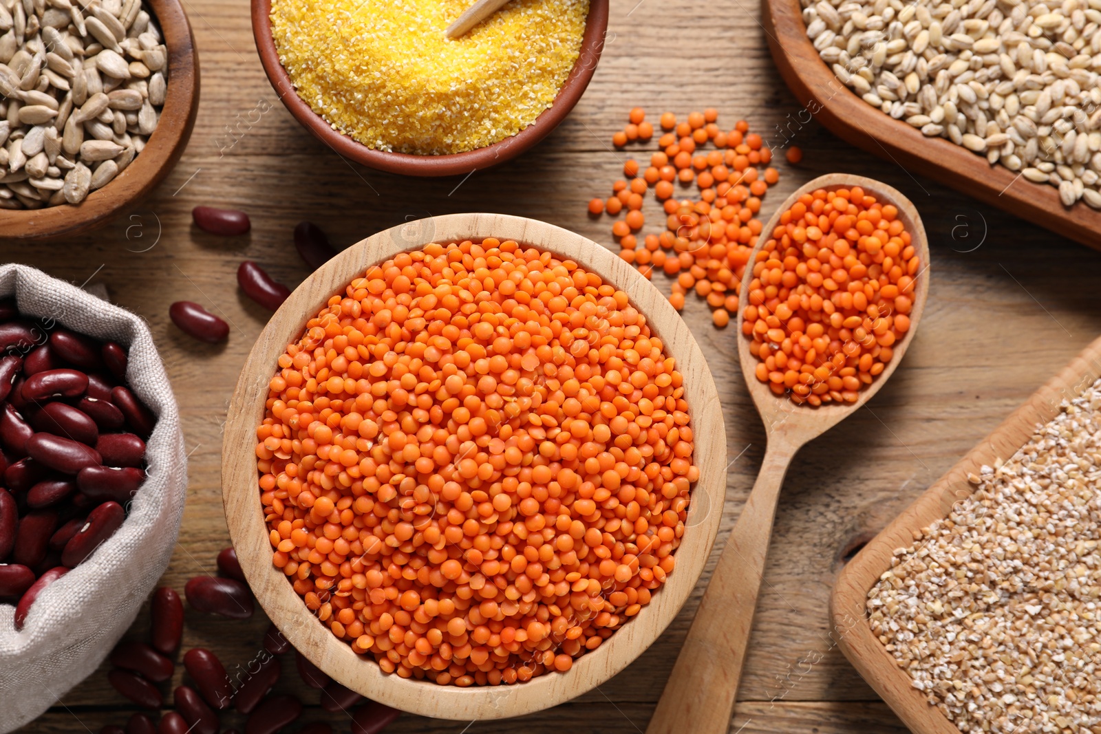 Photo of Different types of cereals, seeds and legumes on wooden table, flat lay