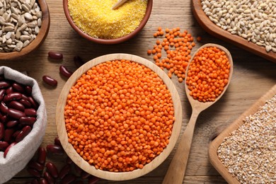 Photo of Different types of cereals, seeds and legumes on wooden table, flat lay