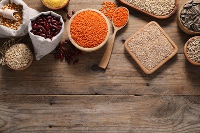 Photo of Different types of cereals, seeds and legumes on wooden table, flat lay. Space for text