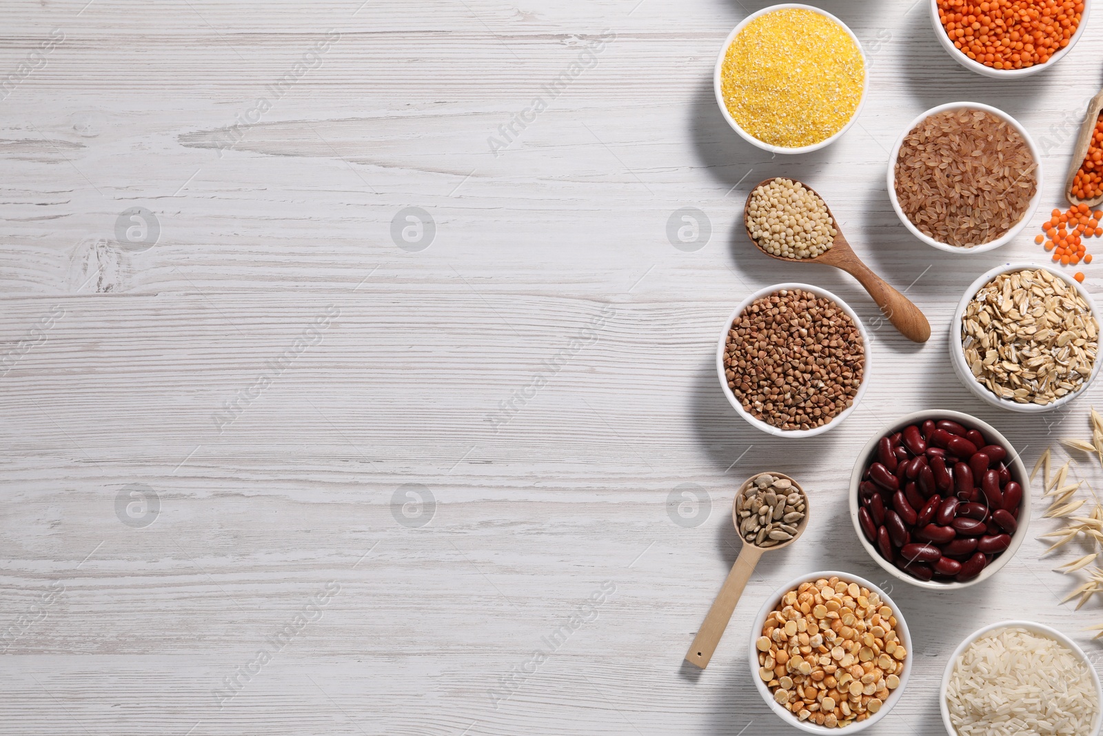 Photo of Different types of cereals, seeds and legumes on white wooden table, flat lay. Space for text