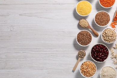 Photo of Different types of cereals, seeds and legumes on white wooden table, flat lay. Space for text