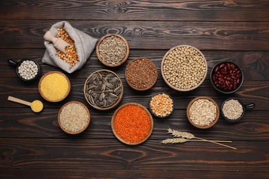 Photo of Different types of cereals, seeds and legumes on wooden table, flat lay