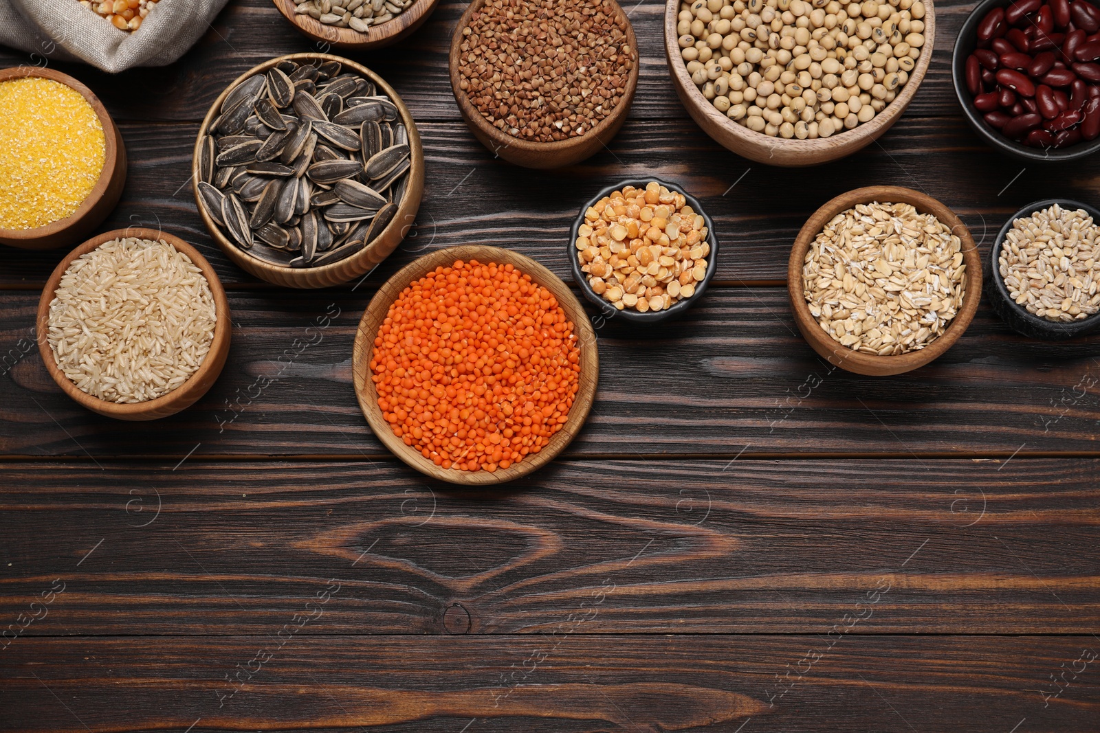 Photo of Different types of cereals, seeds and legumes on wooden table, flat lay. Space for text