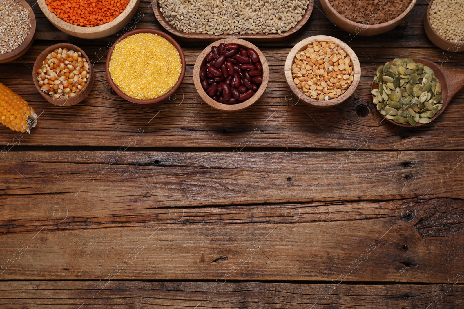 Photo of Different types of cereals, seeds and legumes on wooden table, flat lay. Space for text