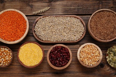 Photo of Different types of cereals, seeds and legumes on wooden table, flat lay