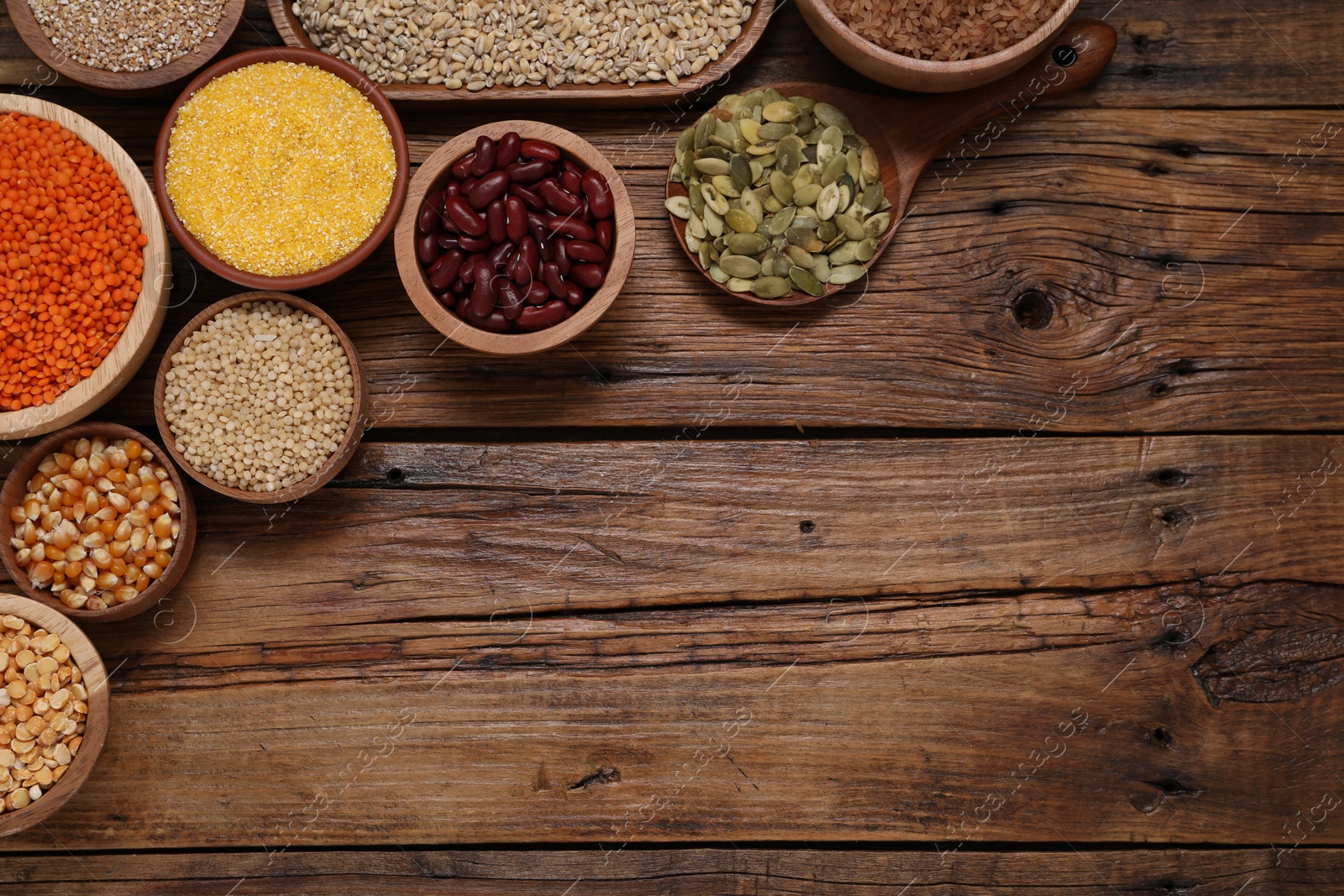 Photo of Different types of cereals, seeds and legumes on wooden table, flat lay. Space for text