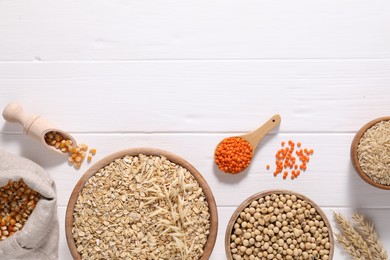 Photo of Different types of cereals and legumes on white wooden table, flat lay. Space for text