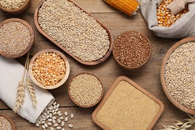 Photo of Different types of cereals and legumes on wooden table, flat lay