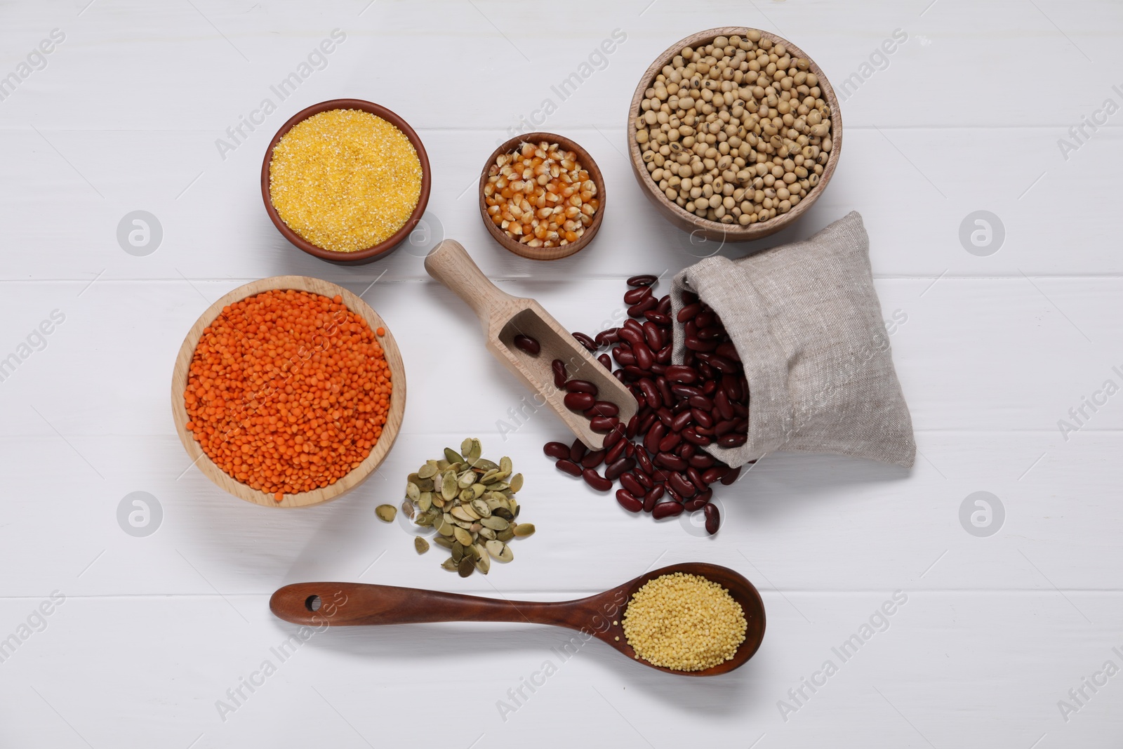 Photo of Different types of cereals, seeds and legumes on white wooden table, flat lay