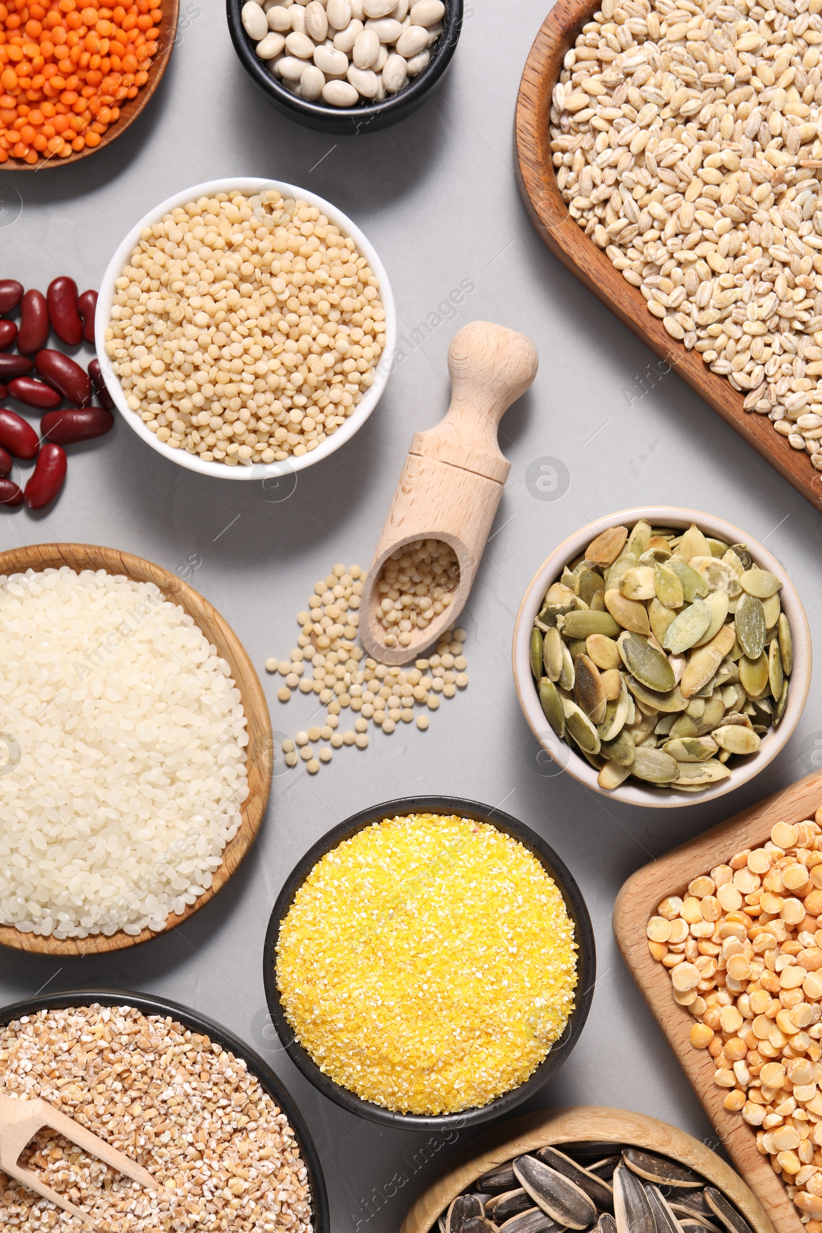 Photo of Different types of cereals, seeds and legumes on grey table, flat lay