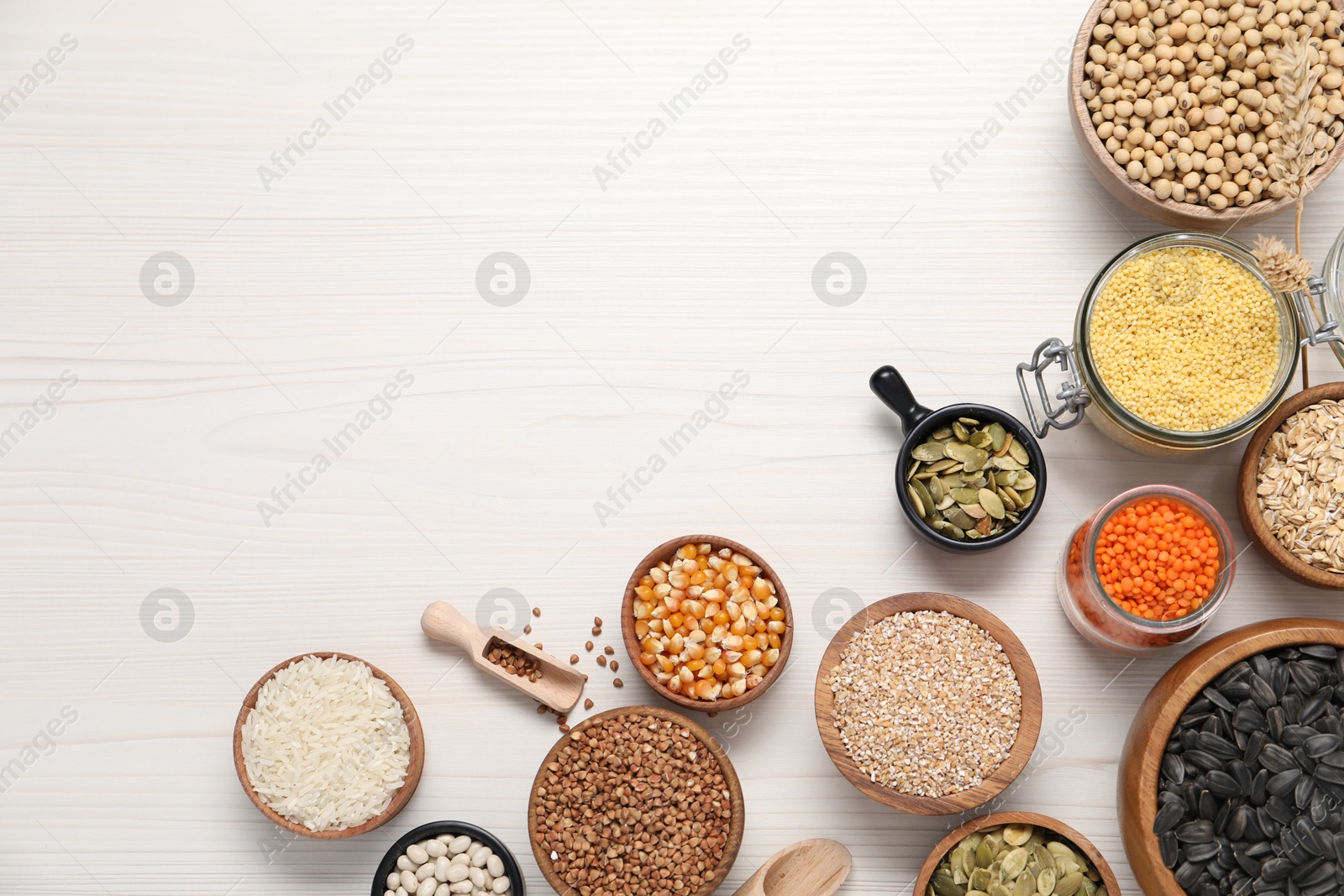 Photo of Different types of cereals, seeds and legumes on white wooden table, flat lay. Space for text