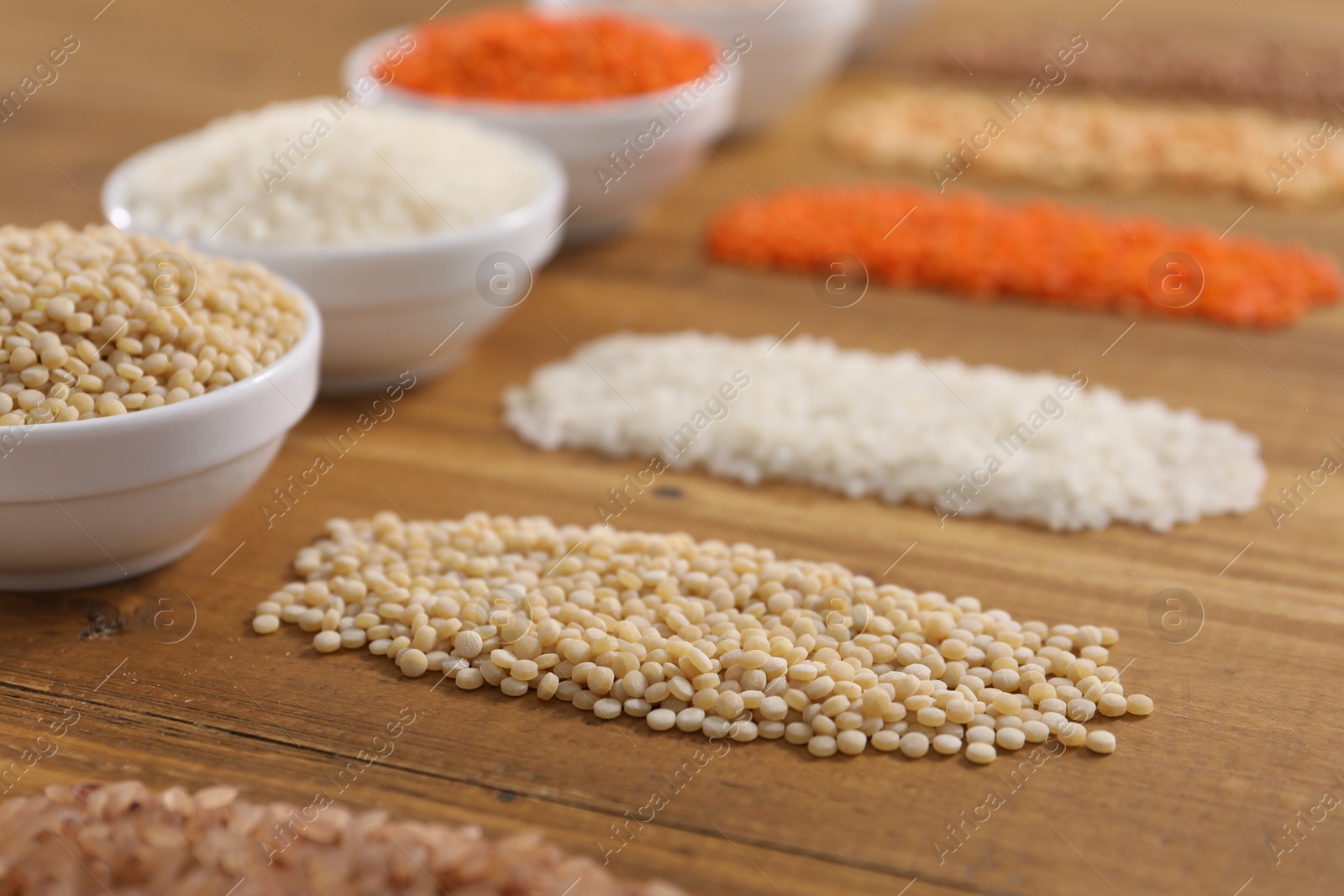 Photo of Different types of cereals and legumes on wooden table, closeup