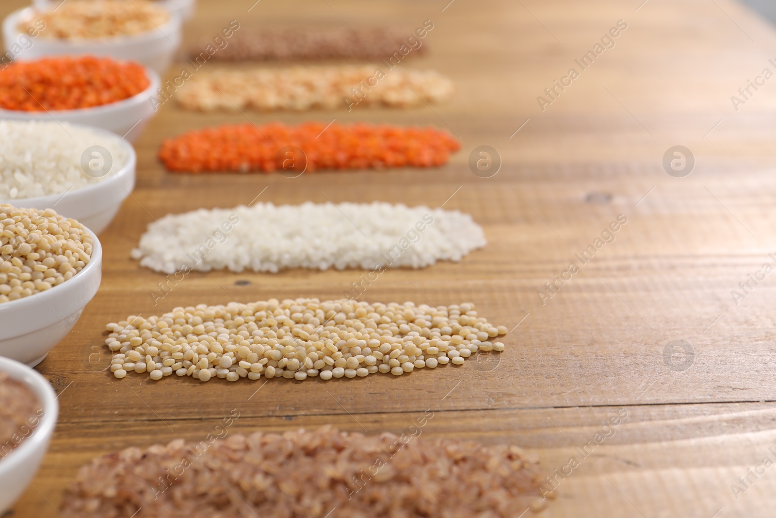 Photo of Different types of cereals and legumes on wooden table, closeup