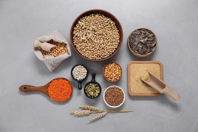 Photo of Different types of cereals, seeds and legumes on grey textured table, flat lay