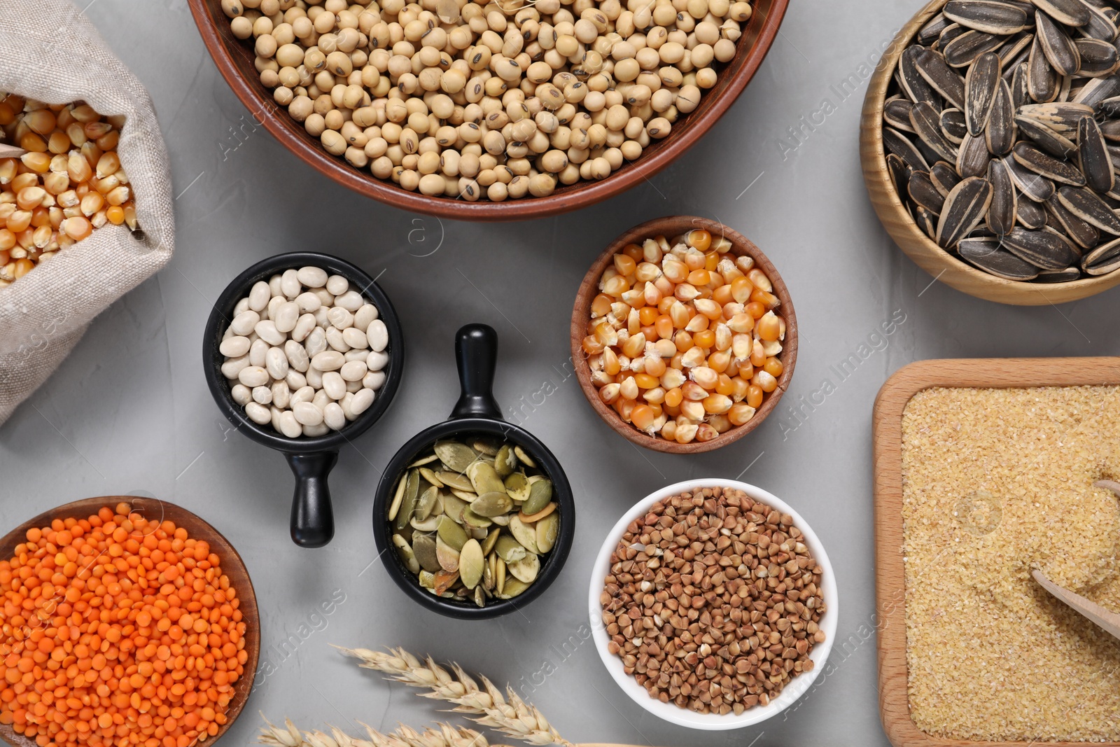 Photo of Different types of cereals, seeds and legumes on grey textured table, flat lay