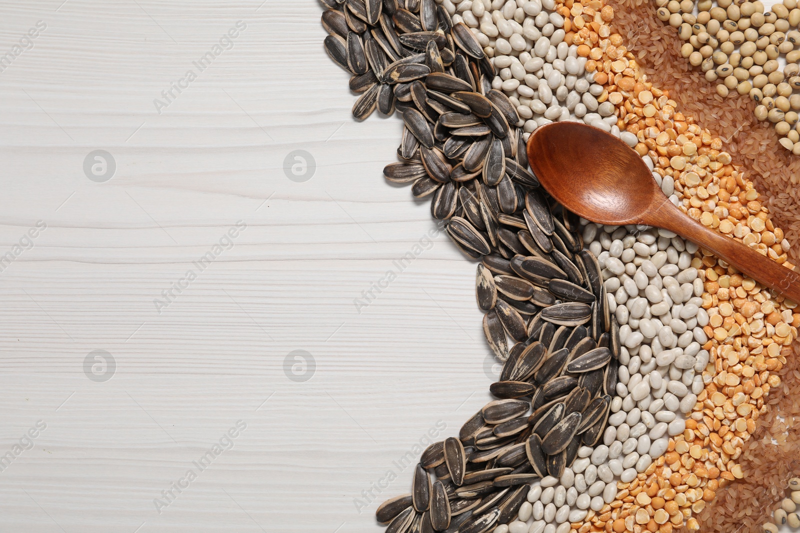 Photo of Different types of cereals, seeds and legumes with spoon on white wooden table, flat lay. Space for text