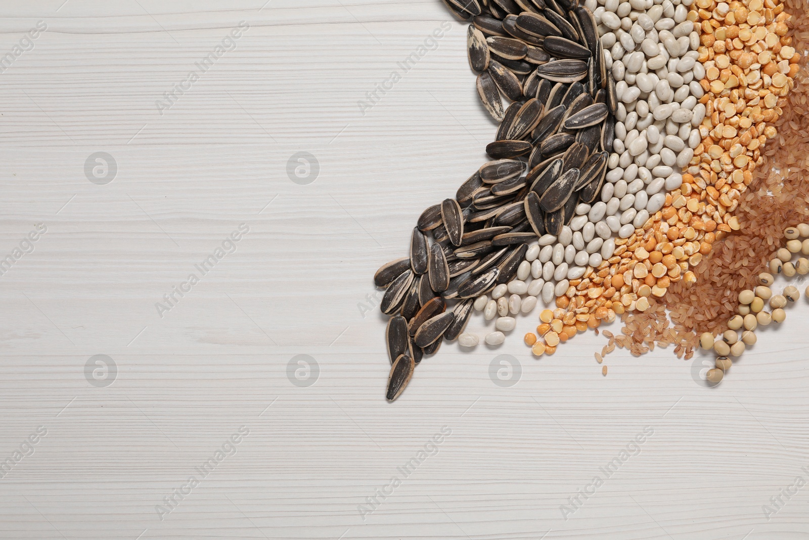 Photo of Different types of cereals, seeds and legumes on white wooden table, flat lay. Space for text