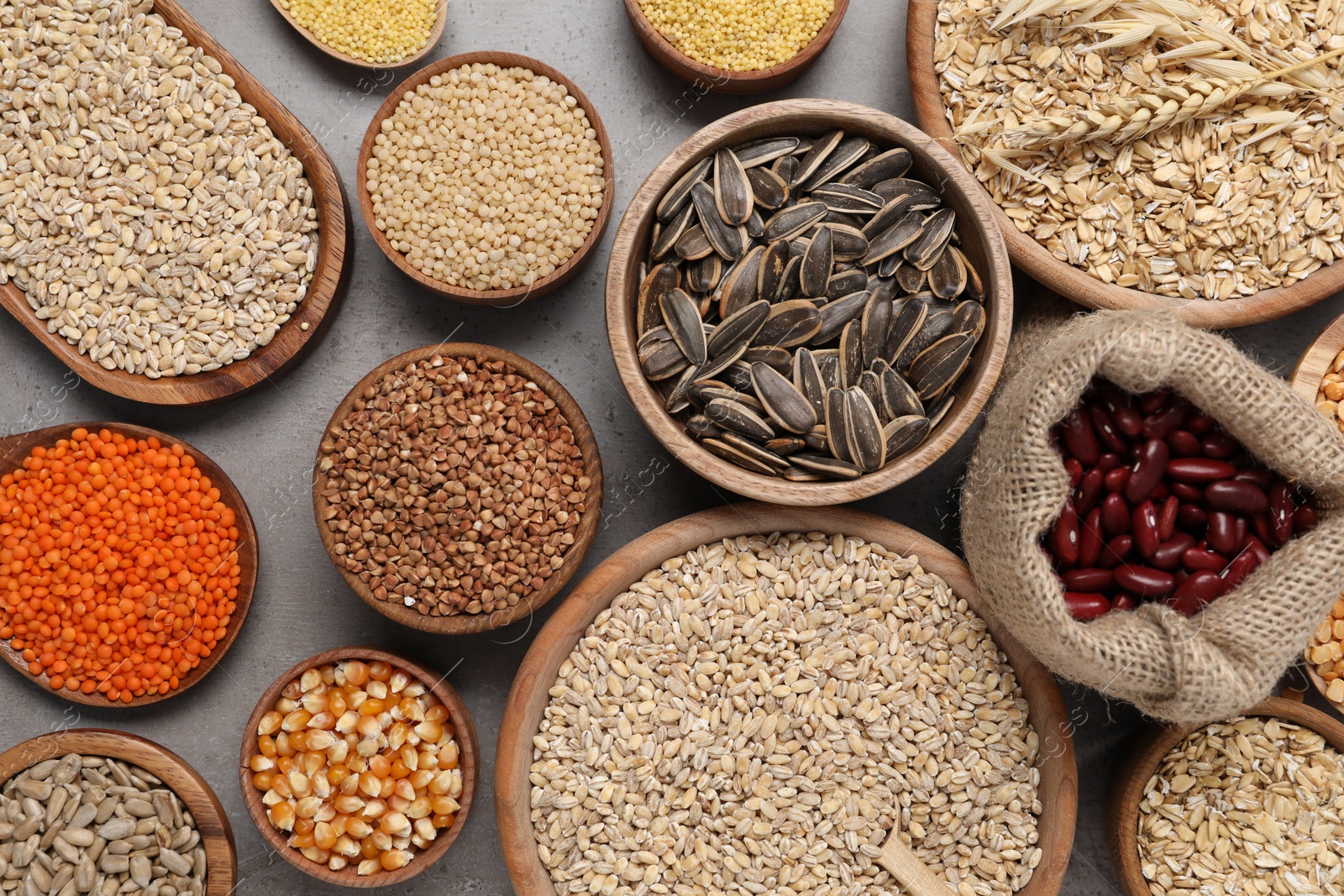 Photo of Different types of cereals, seeds and legumes on grey table, flat lay