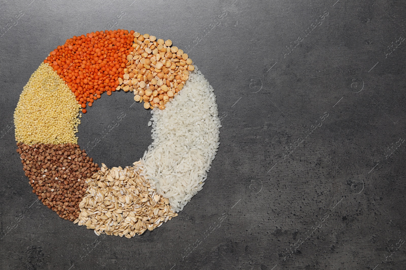 Photo of Different types of cereals and legumes on grey table, top view. Space for text